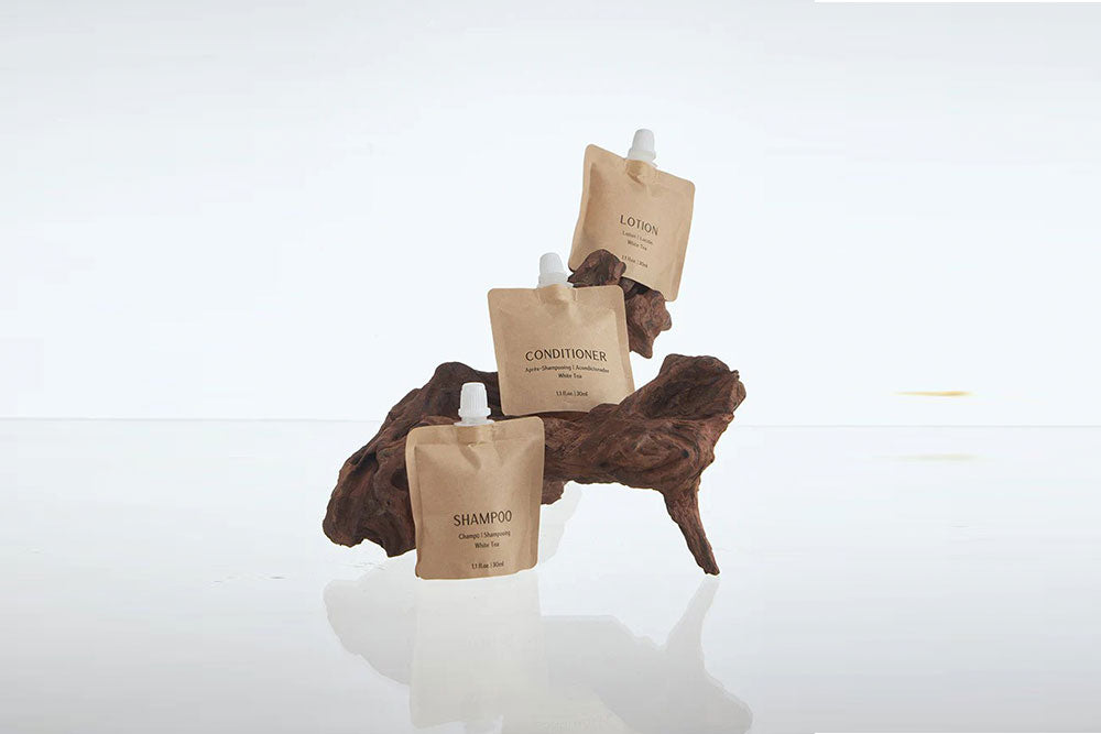 Paper-based shampoo packaging for hotels displayed with eco-friendly conditioner and lotion sachets