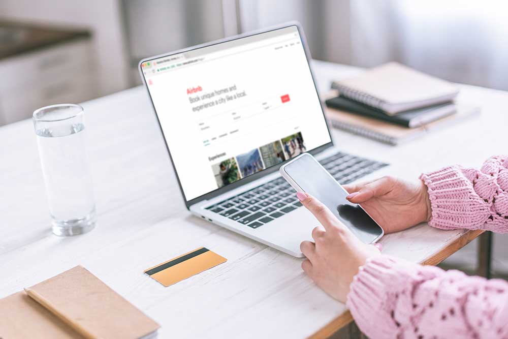 Cropped view of woman holding smartphone near laptop