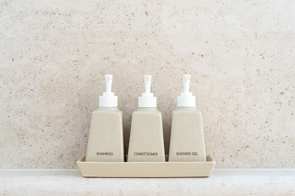 Minimalist hotel amenities packaging with labeled refillable toiletry bottles