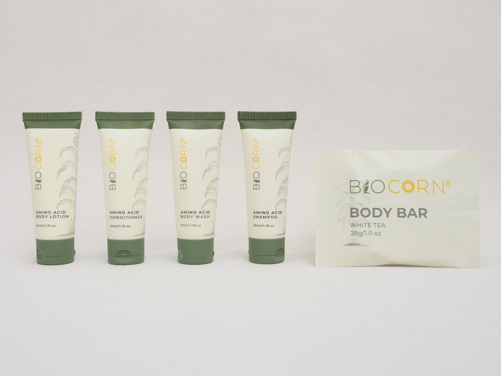 Set of Biocorn skincare products including body lotion, shampoo, conditioner, and a body bar on a white background.