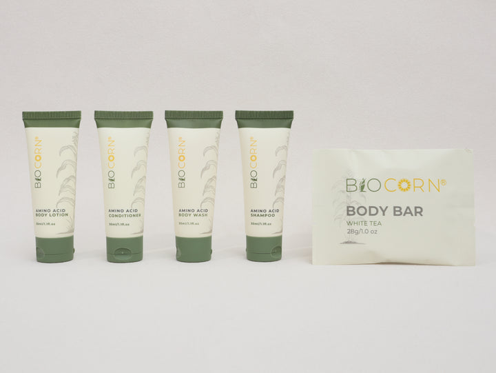 Set of Biocorn skincare products including body lotion, shampoo, conditioner, and a body bar on a white background.